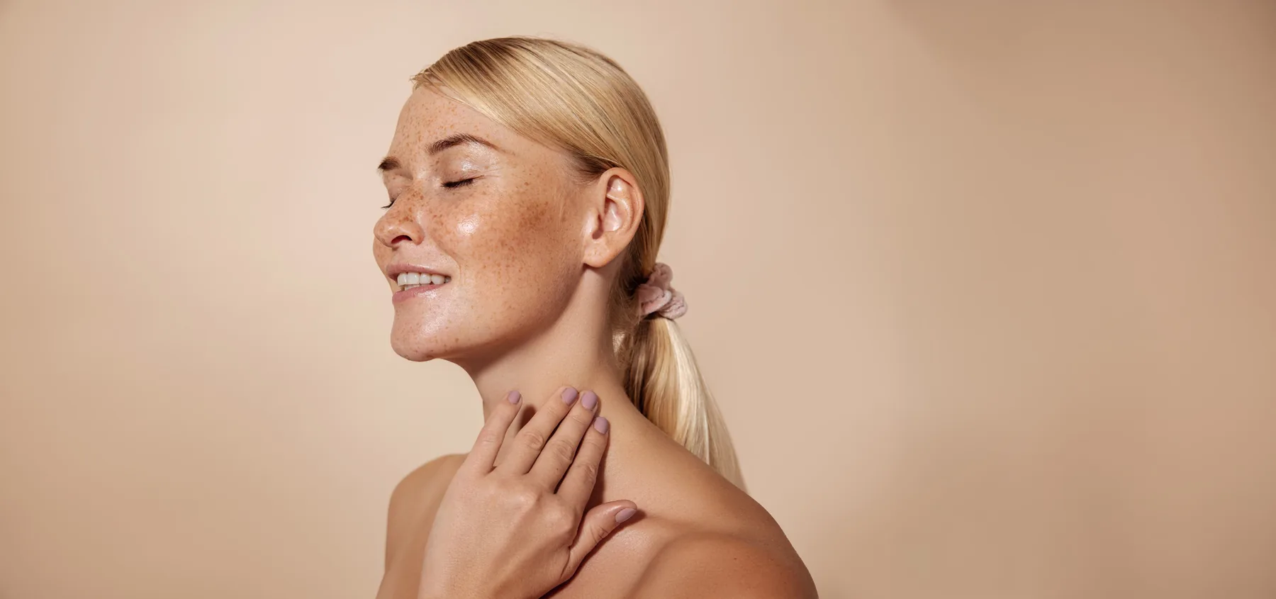 Mujer sonriente con los ojos cerrados tocándose el cuello